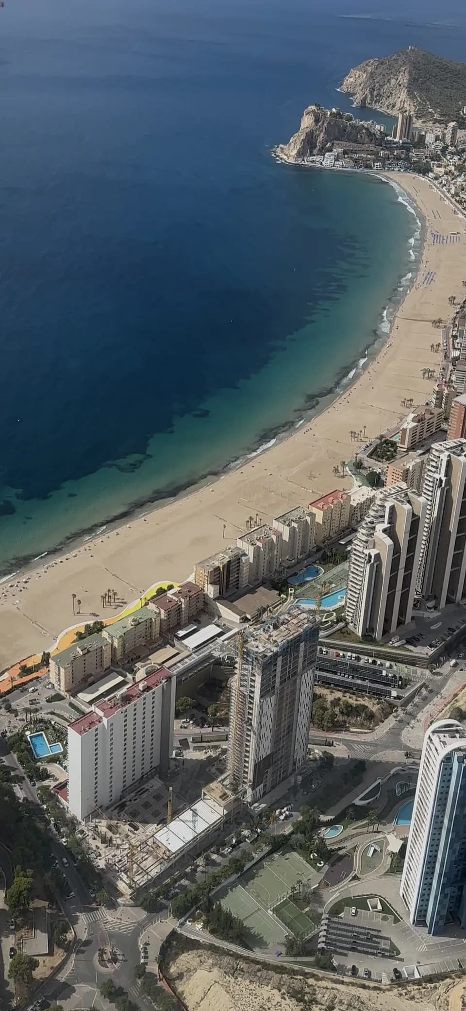 Playa curva y mar turquesa desde el aire